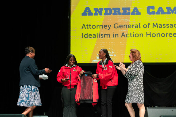 four people up on stage two are wearing red City Year jackets