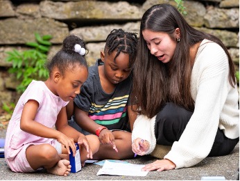 Woman drawing with two kids outside