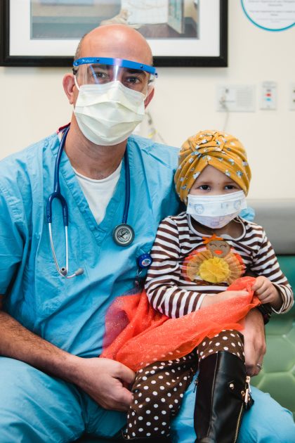 doctor holding a little girl with a colorful headscarf on