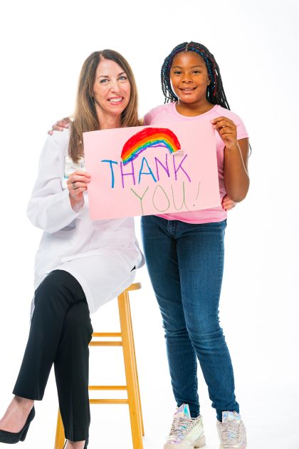 doctor and girl holding a sign that says thank you