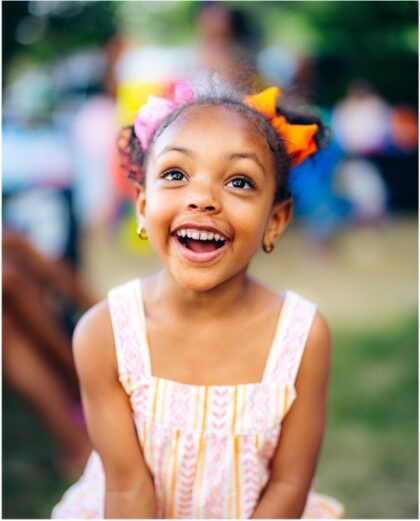 Little girl smiling with ribbons in her hair.