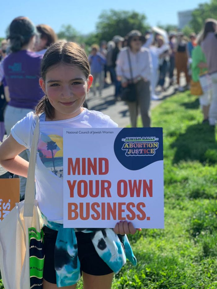 young girl holding a sign that says mind your own business