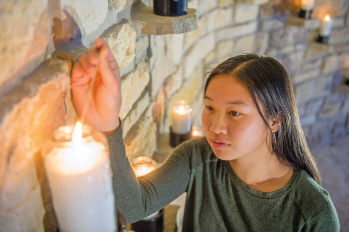 St. Norbert College woman lighting a candle