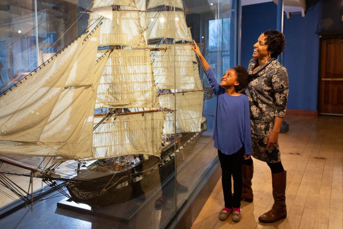a mother and child looking at a smaller uss constitution