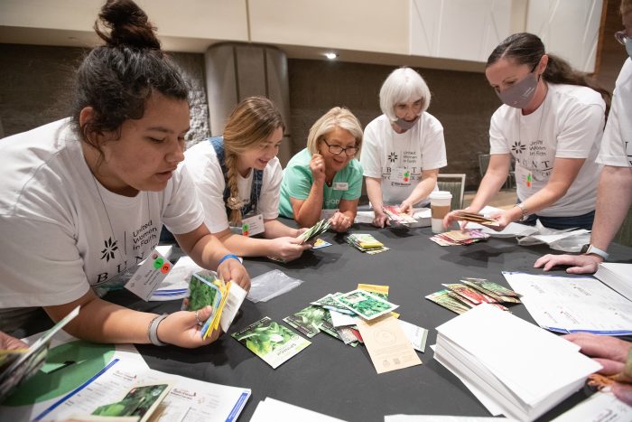 a group of women sorting pamphlets for united women in faith